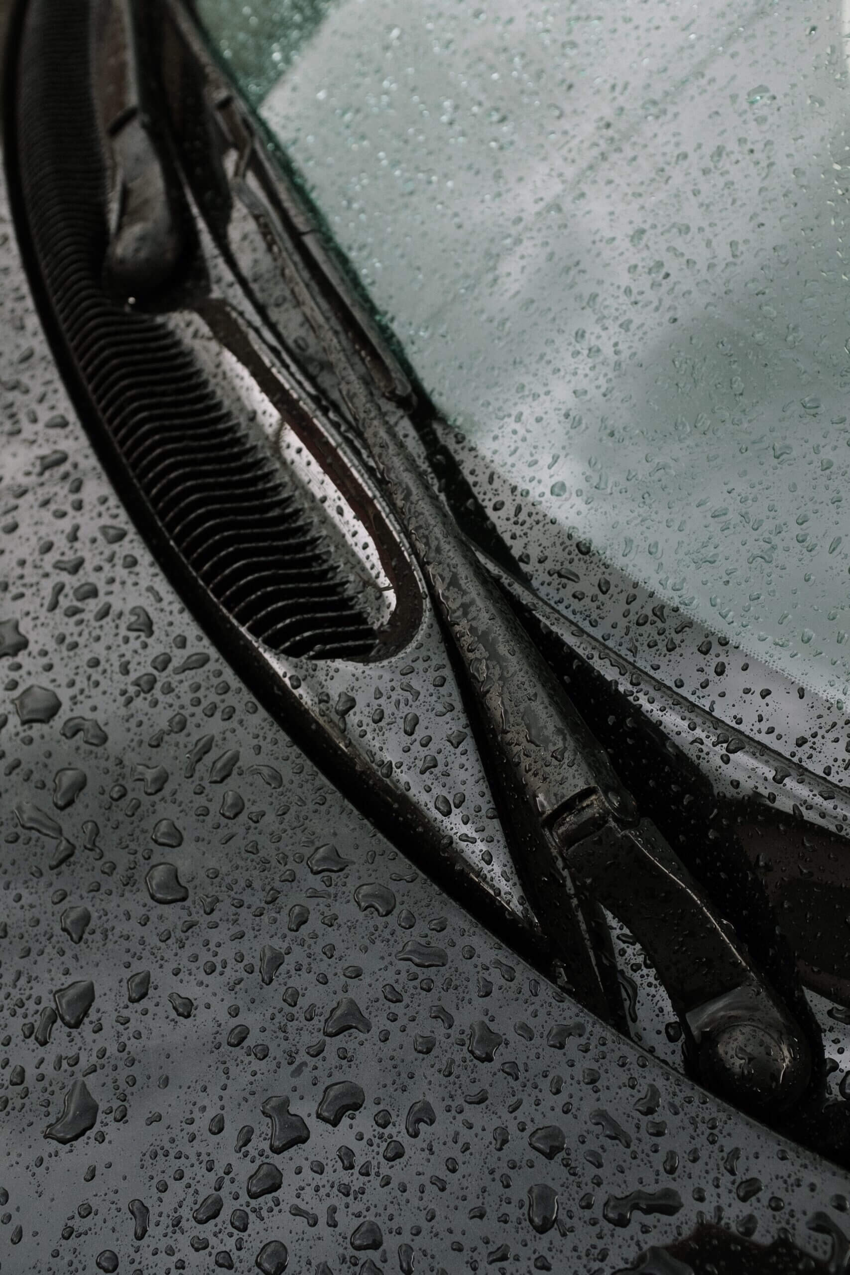 Black car with raindrops and windshield wiper.